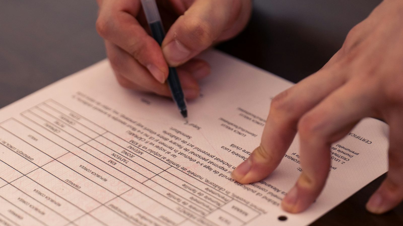 Hands signing an insurance form with a pen